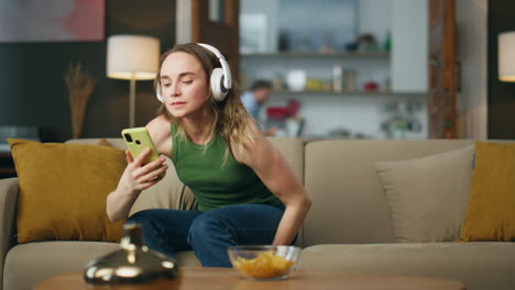 Auriculares-Mujer-Escuchando-Música-Poniendo-Sofá-En-El-Piso.-Chica-Relajada-Sentada-En-El-Sofá