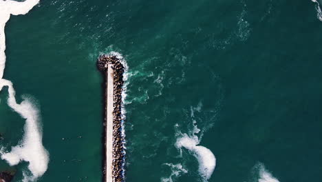 Pier,-Der-Auf-Einer-Seite-Durch-Dolosse-Vor-Tosenden-Wellen-Geschützt-Ist