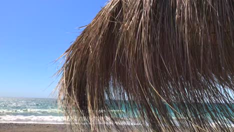 windy day at the beach with a thatch umbrella in marbella malaga spain