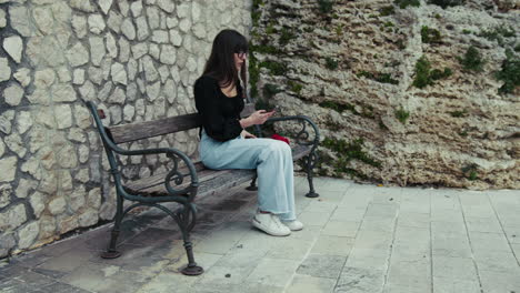 woman on the bench picking up the smartphone to make some photos