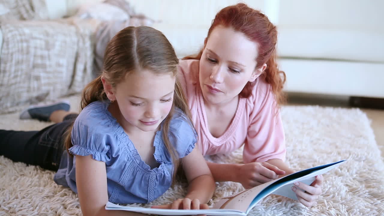 Bambina carina che legge un libro ad alta voce con sua madre