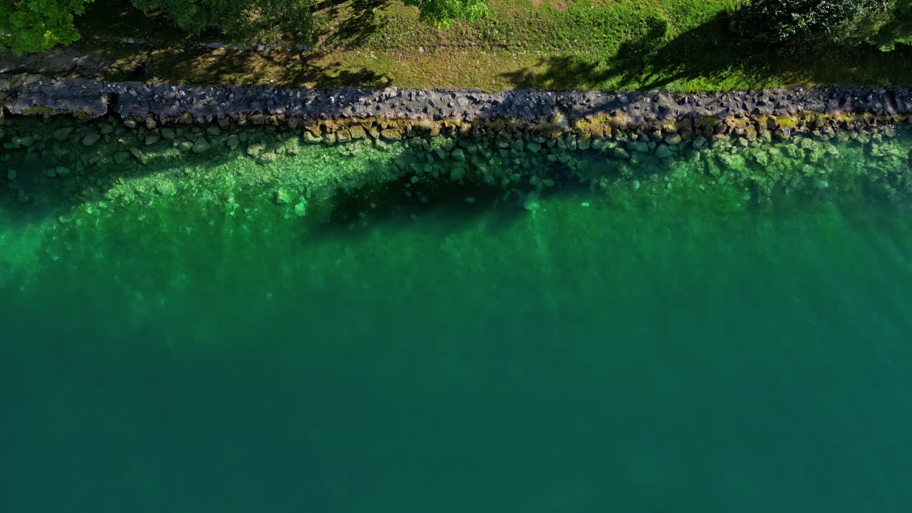 Aerial drone bird's eye view of a rocky lake shore with a small dock