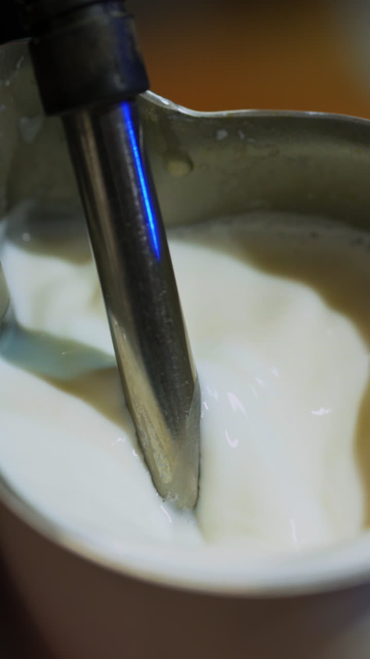 Hot milk pouring from coffee machine. Making fresh coffee with milk. Process of cappuccino preparation. Close-up. Vertical video