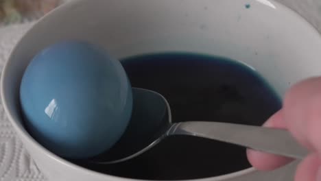 painting an eastern egg in a bowl of water and blue color