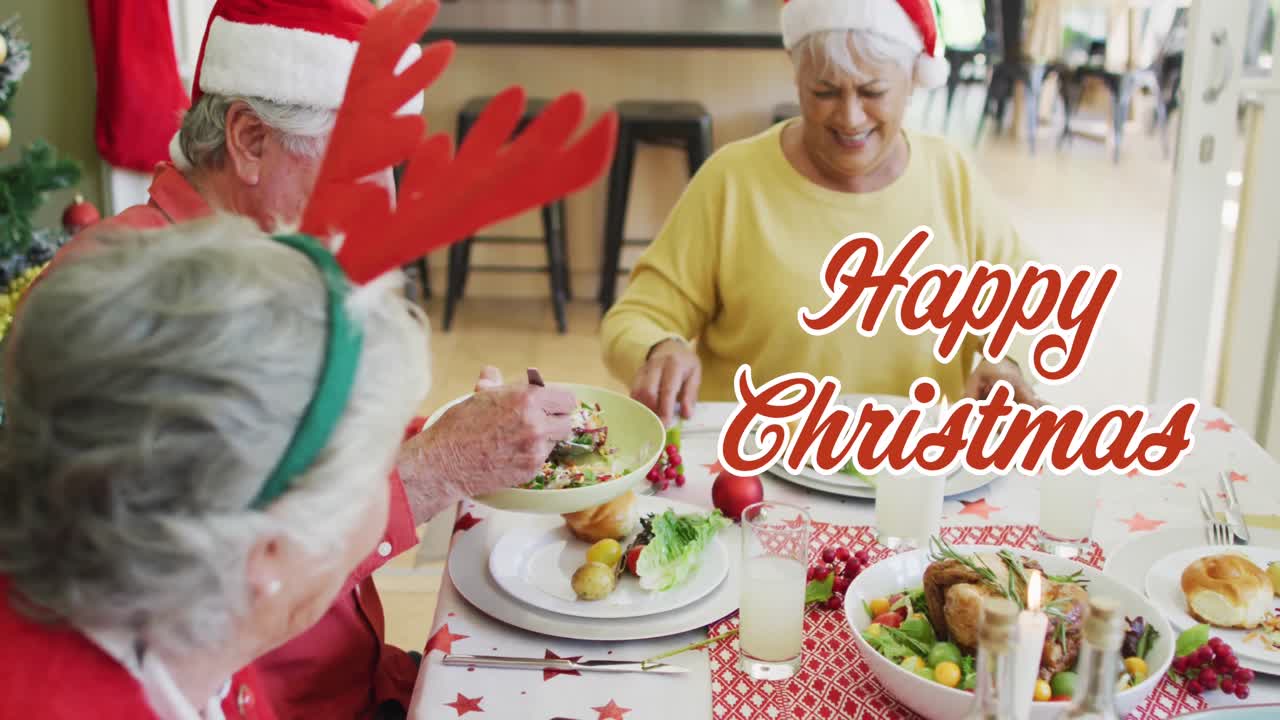 animación de feliz texto de navidad sobre diversos amigos mayores riendo en la mesa de la cena de navidad.