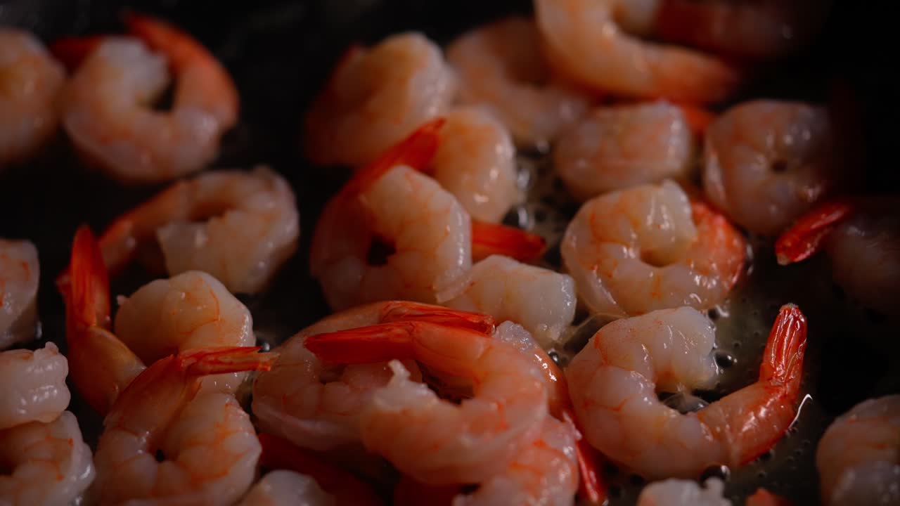 Close-up of shrimp browning in pan with bubbling oil and golden color forming on surface