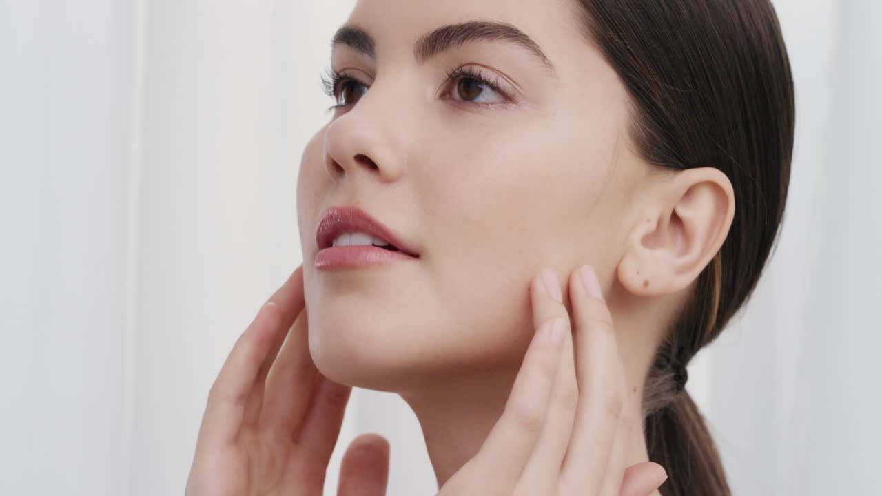 retrato de cerca de una mujer joven hermosa tocando suavemente la piel con las manos acariciando una tez suave y suave sonriendo disfrutando de una belleza natural perfecta concepto de cuidado de la piel de lujo