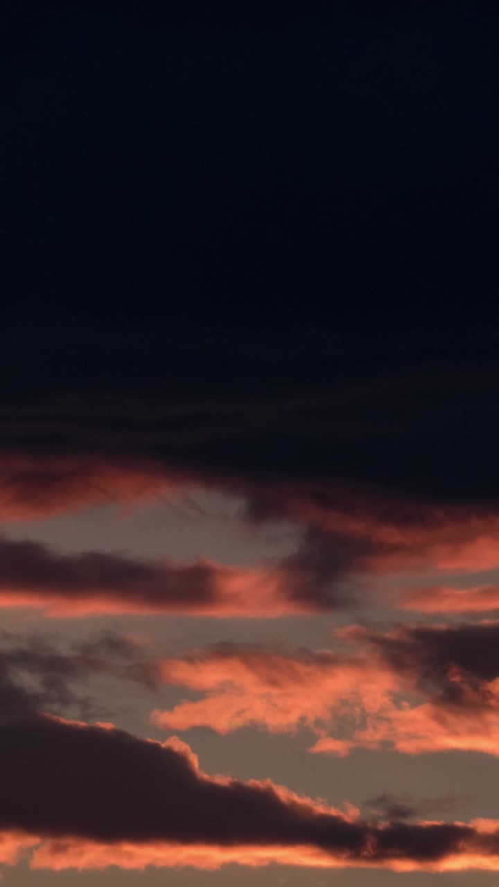 Zeitraffer von lebendigen Sonnenuntergangswolken vor einem dunklen Himmel
