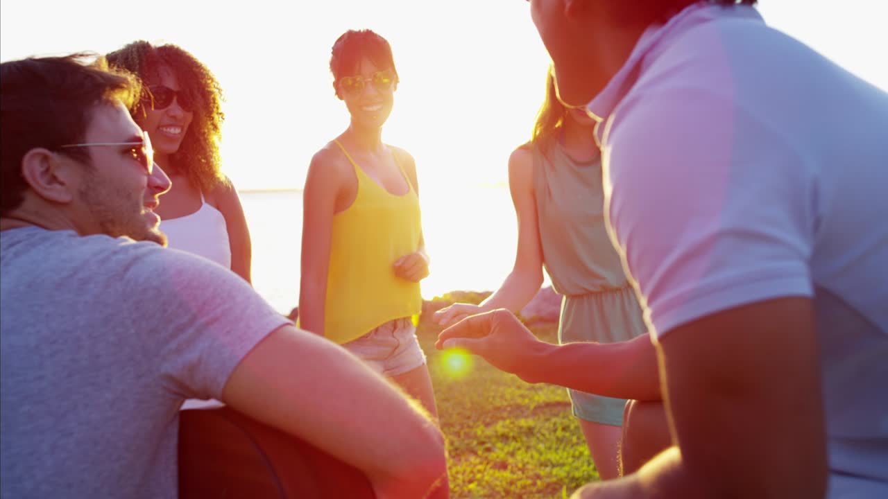 해변에서 기타를 연주하고 춤을 추는 다민족 친구들