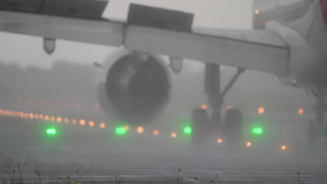 close-up view of aircraft landing gear and engine on runway during heavy rain
