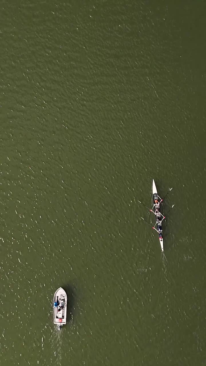 Aerial View of Rowers in a Scull with a Motorboat on Green Water