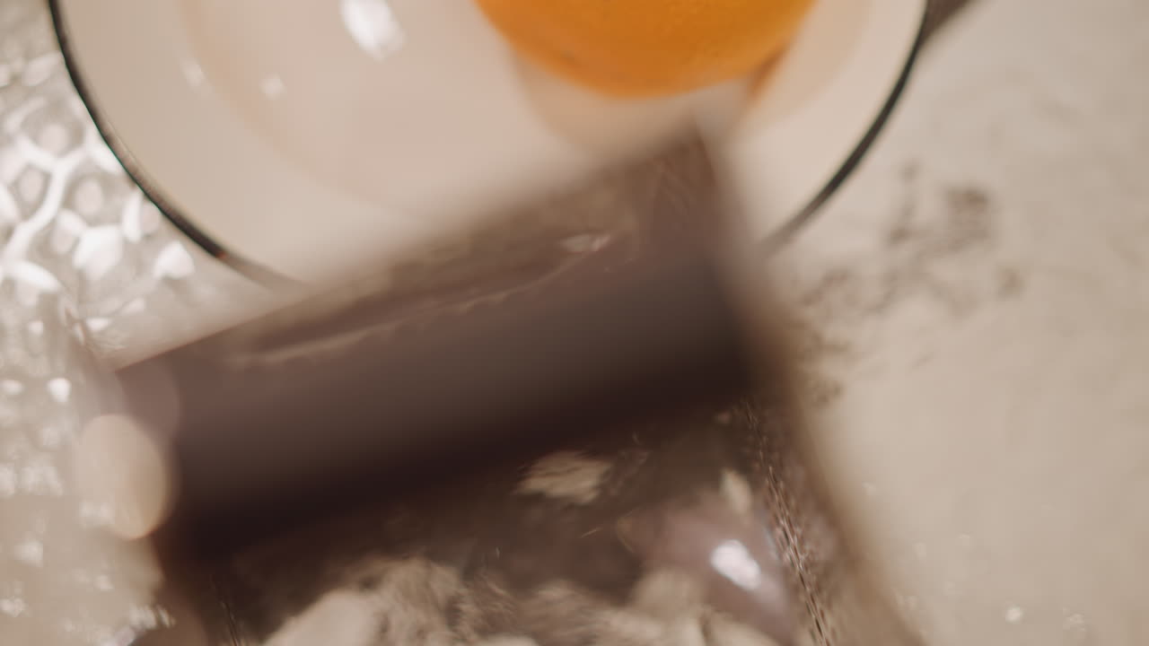 Chef demonstrates citrus zesting technique. Closeup of grater motion over bowl showing beautiful zesting process. Chef skillfully demonstrates how to grate orange peel over warm porcelain bowl