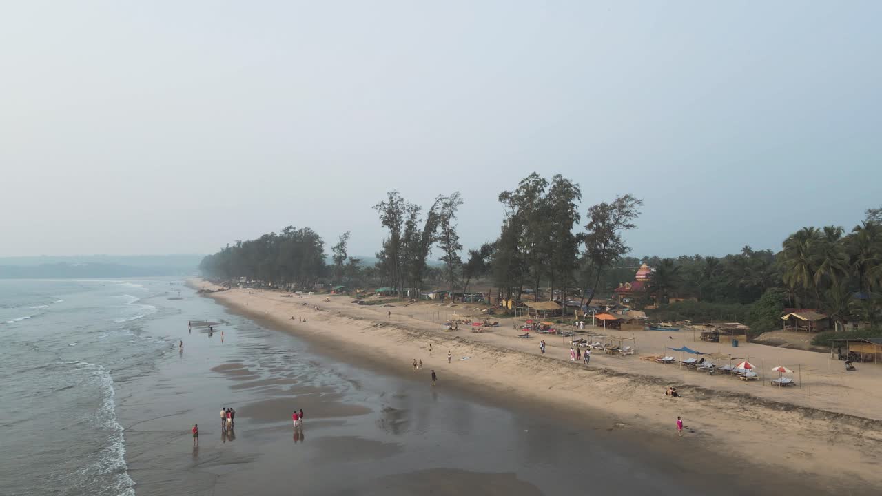 drone vuela por encima de la gente y las palmeras en la playa de arena