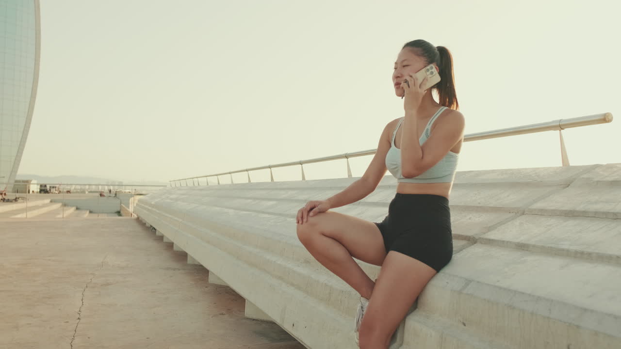 スポーツウェアを着た女性が屋外で電話をしている