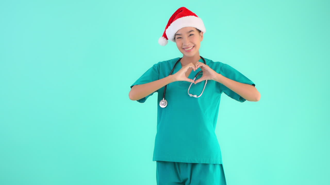 Dottoressa con cappello di Natale che fa il segno del cuore. Copia spazio SLOMO