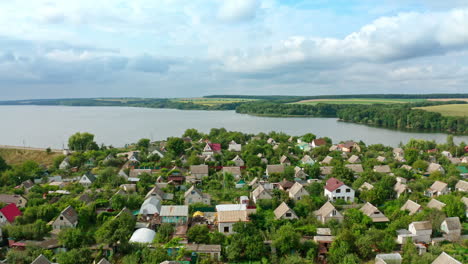 countryside near the river in summer. flying over village houses on nature background. rural buildings with green plantings. aerial view.