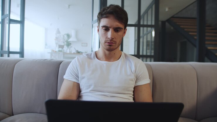 Konzentrierter Geschäftsmann blickt zu Hause auf den Laptop-Bildschirm