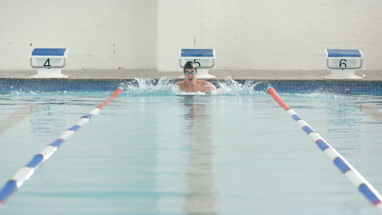 Swimming in pool, male swimmer practicing breaststroke in competition lane, copy space