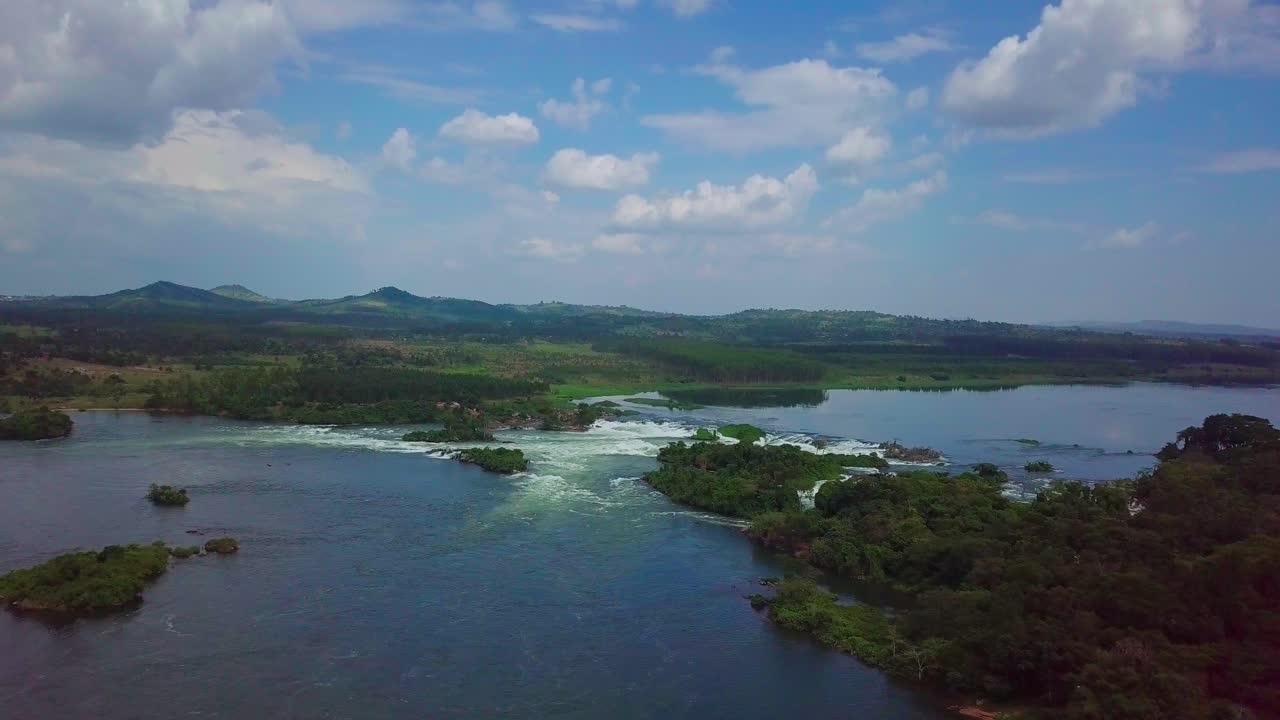 Aerial view of the source of the Nile River with its rapids and waterfalls flowing through the green lush landscape of Uganda, Africa, under a cloudy sky