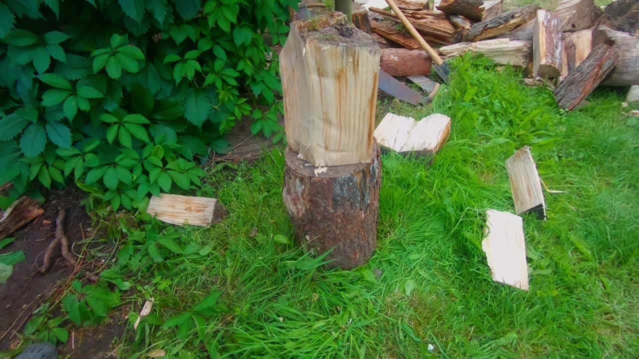 A Man With An Ax Splits Firewood In The Village. Slow Motion Shot