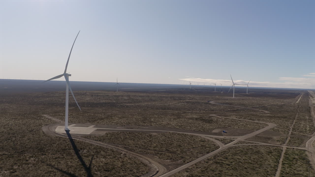 wide-angle aerial clip captures multiple spinning wind turbines across the vast expanse of the Patagonian desert