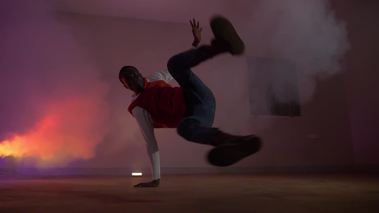 toma en cámara lenta de jóvenes africanos con camisa roja haciendo grandes bengalas con su pierna mientras bailan con luces coloridas y humo
