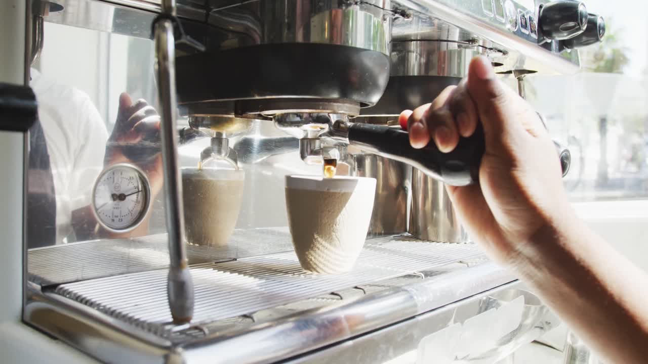 Nærbillede af afroamerikansk mandlig barista, der laver kaffe på en café