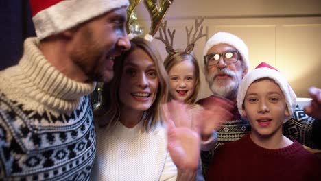 Pov-F-Fröhliche-Schöne-Familie-Mit-Kindern-Zusammen-In-Einem-Geschmückten-Raum-Mit-Leuchtendem-Weihnachtsbaum-Und-Online-Auf-Video-Sprechen-Und-Hände-Winken