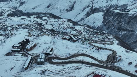 an aerial view of a mountain village surrounded by snow-covered peaks. the winding roads add charm and connect scattered buildings amid a pristine white landscape
