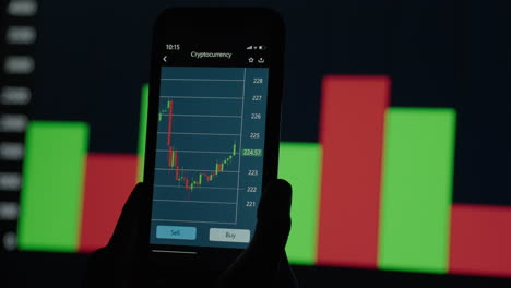 Hands-with-a-mobile-phone-checking-stock-market-data.-Mobile-Phone-Stock-Exchange.-Graphs-and-tables-in-the-background