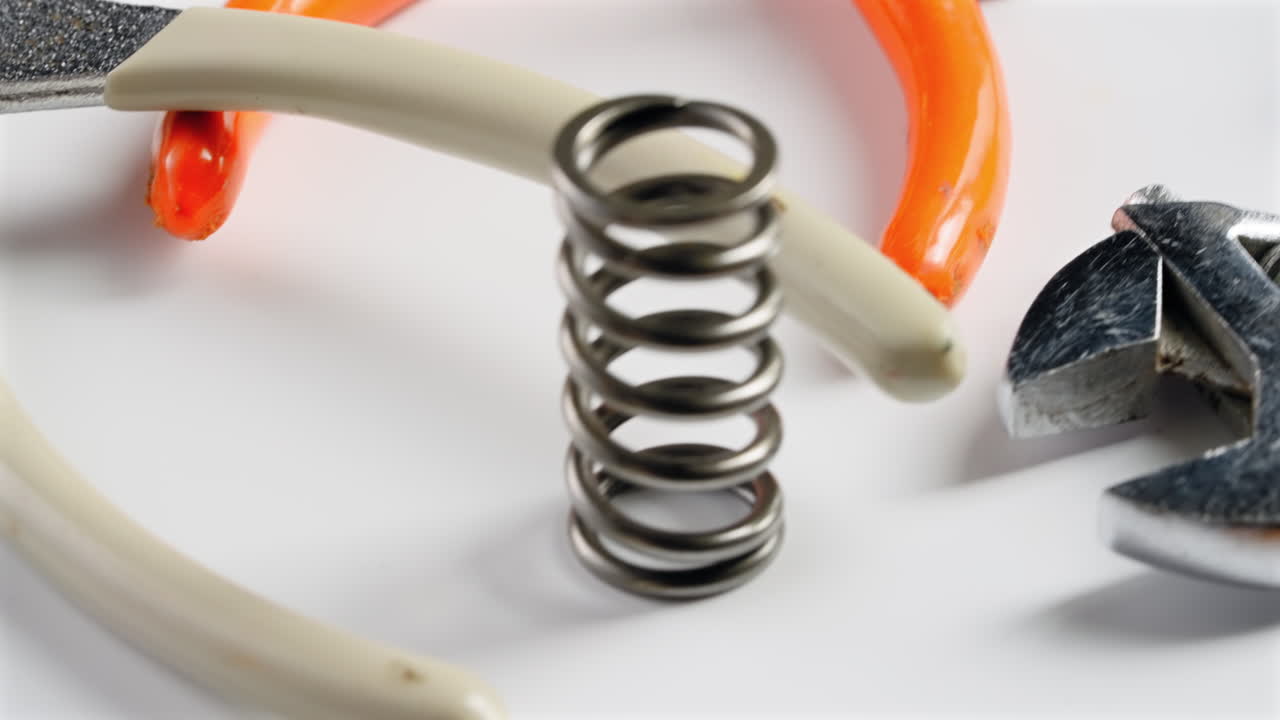 Closeup of Pliers and Large Springs Spinning on a Table