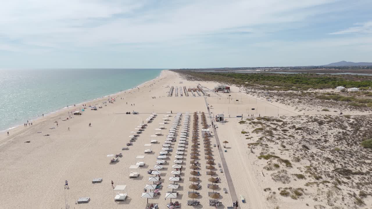 Scenic drone view capturing Tavira Island’s beach activity, including people relaxing on loungers and walking along the shore