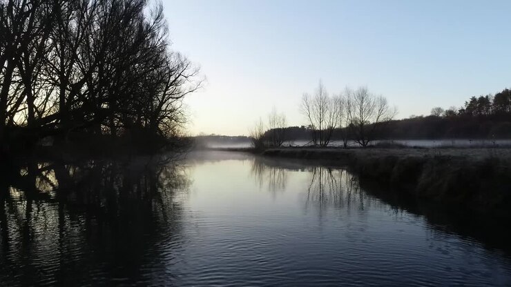 Mattina presto, il sole sorge sul villaggio dove un piccolo fiume scorre attraverso il paese vicino a un campo vuoto coperto di nebbia e brina sull'erba. Il tempo è bello e il cielo è azzurro