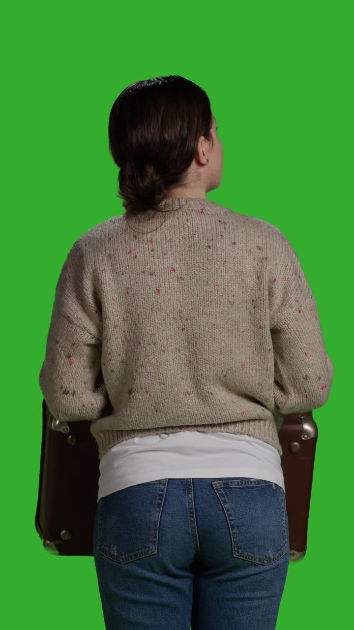 Vertical video: Back view of young woman carrying vintage briefcase