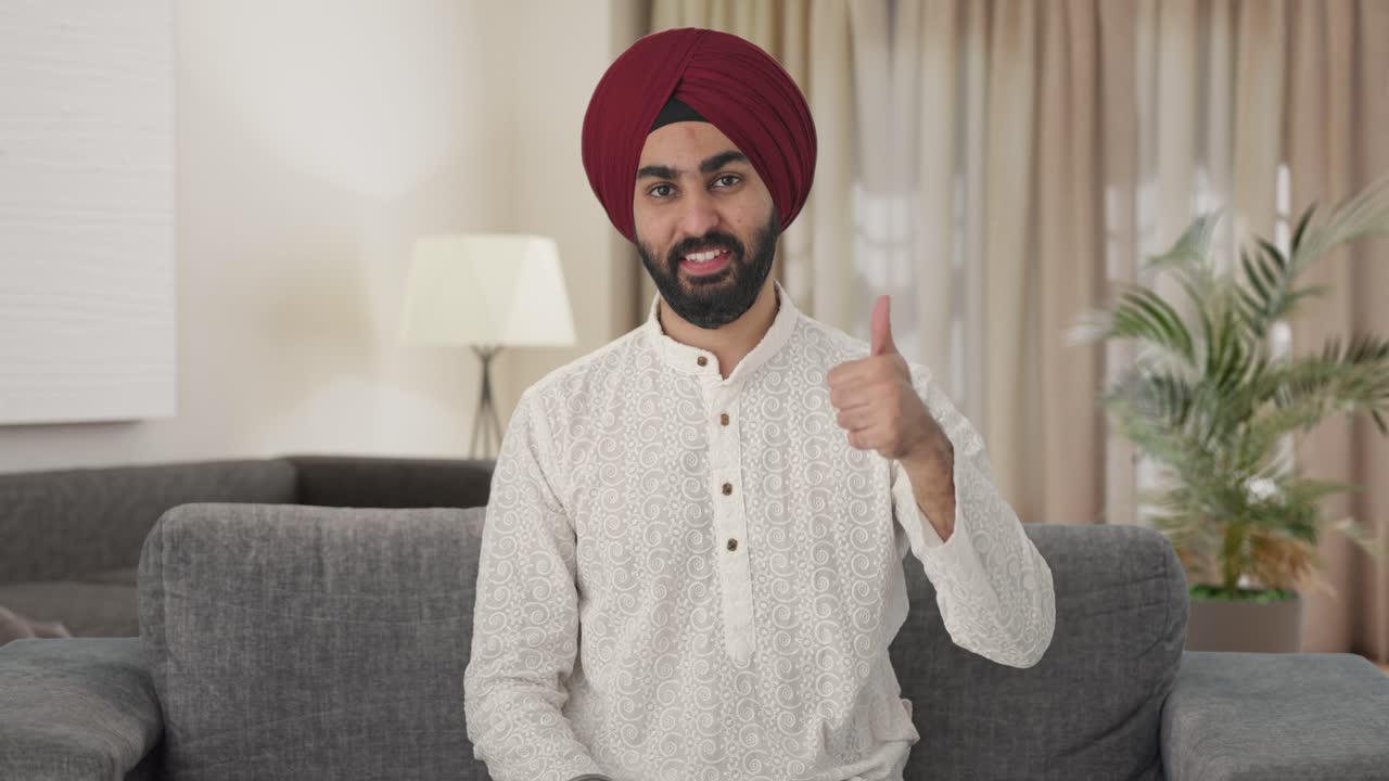 Uomo indiano Sikh felice che mostra il pollice in su