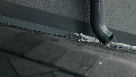 melting snow draining from roof gutter