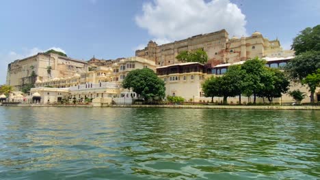 Segeln-An-Einem-Klaren,-Sonnigen-Tag-Am-Stadtpalast-Von-Udaipur-Am-Ufer-Des-Pichola-Sees-Vorbei