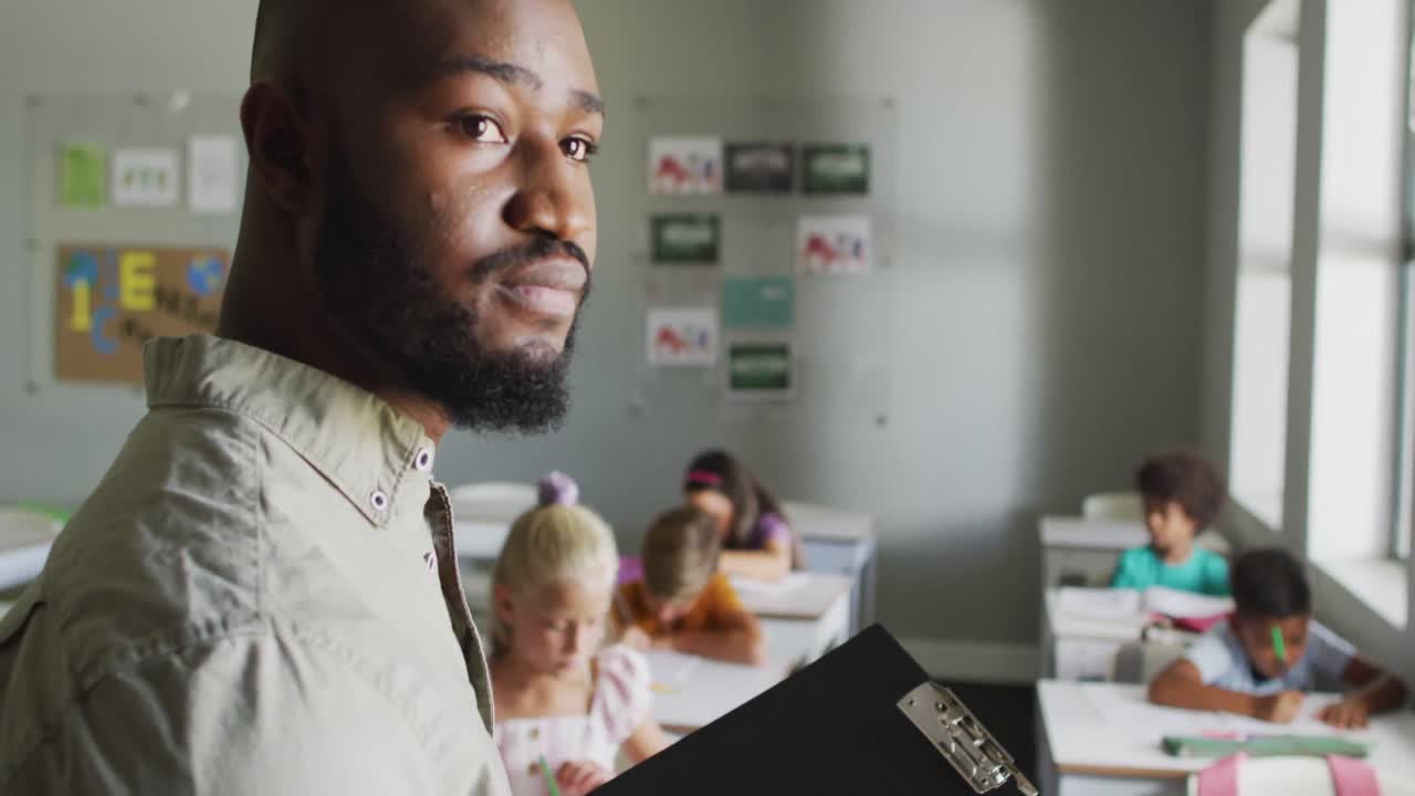 Video of focused african american male teacher during lesson with class of diverse pupils