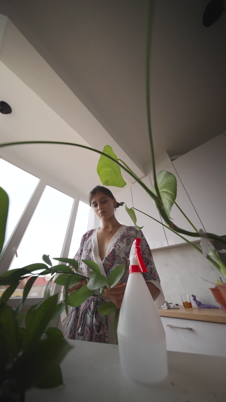 Woman Caring for Houseplants in a Kitchen