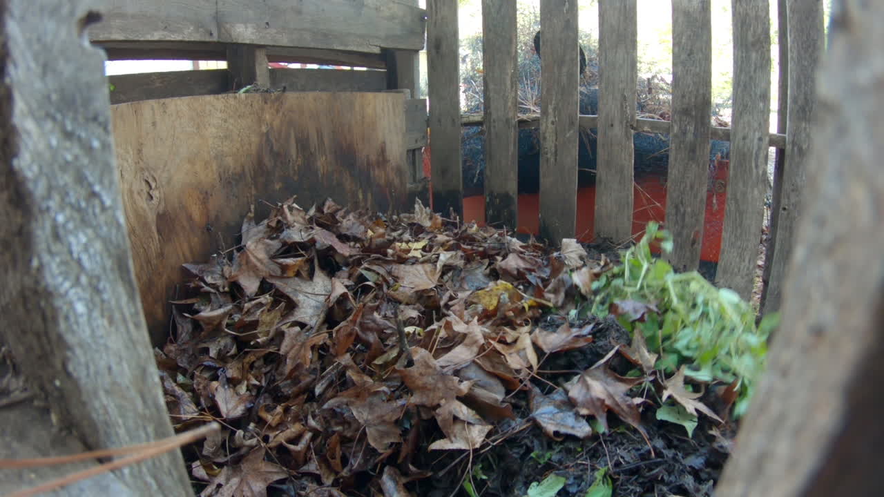 더미에 낙엽을 추가하는 diy 팔레트 퇴비통 내부를 보고 있습니다.