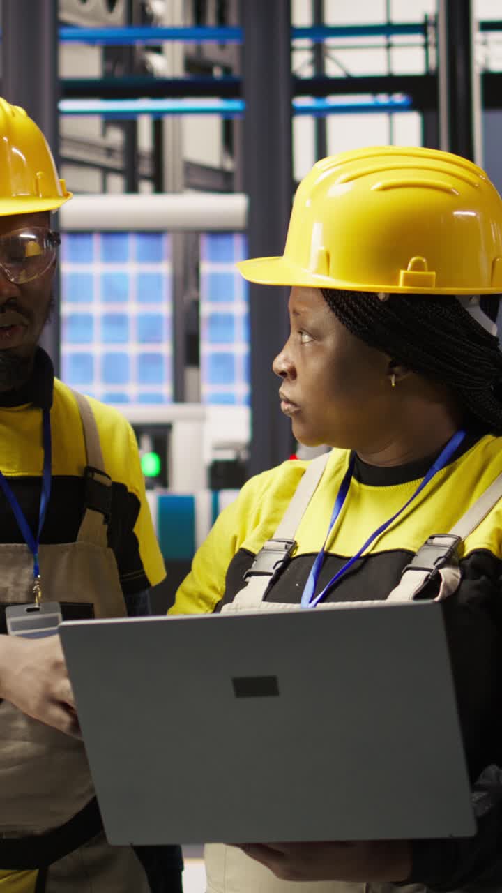 Vertical video Smart factory engineering team using laptop to calibrate high tech machinery