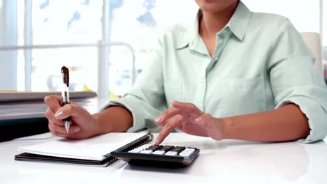 Businesswoman calculating at her desk