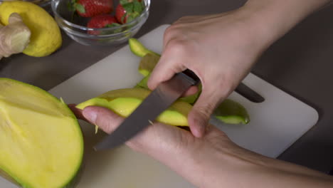 hands peeling a ripe mango in the kitchen for snack. - close up shot