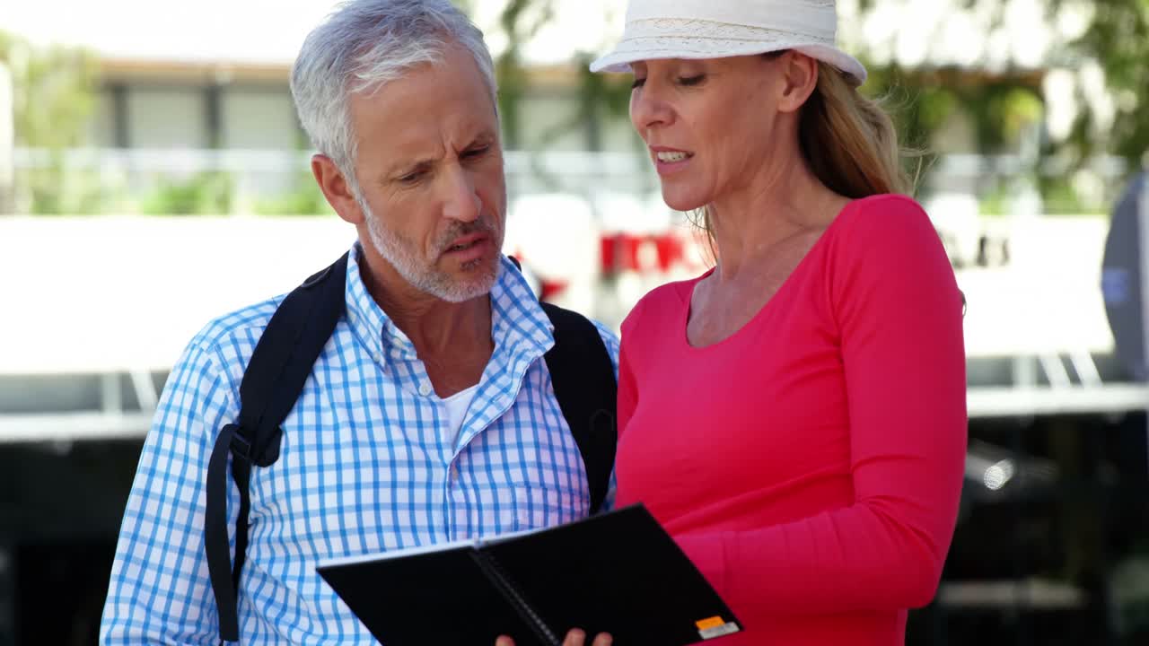una pareja madura está buscando un libro en la calle.