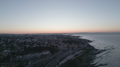 video aéreo de la zona residencial costera durante la puesta del sol, carretera con tráfico de automóviles a lo largo de la costa, concepto de vida costera