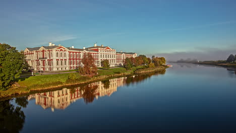 Time-lapse-shot-of-Jelgava-Palace-or-historically-Mitau-Palace-during-sunset-in-Latvia---Reflection-in-water-of-Lielupe-River