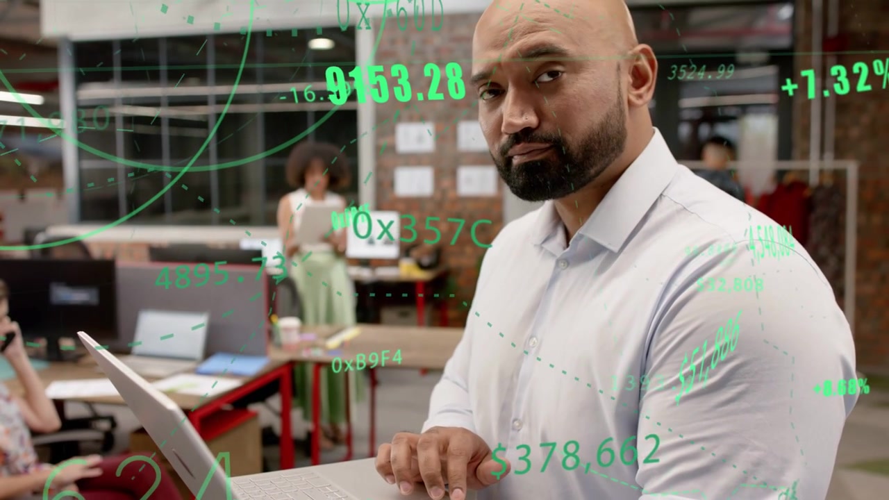 Homem segurando laptop no escritório, digitando e gerando gráficos financeiros verdes para a equipe enquanto a câmera se aproxima.