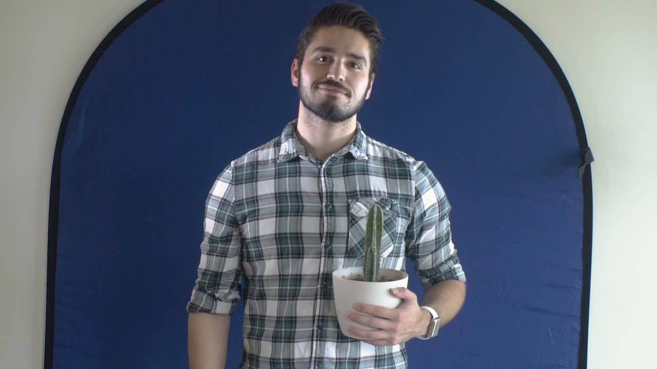joven con cactus frente a la pantalla azul