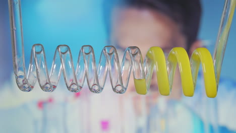 fluido amarillo que fluye en espiral horizontalmente de izquierda a derecha. condensador de laboratorio científico. experimento de laboratorio científico. desarrollo de una vacuna contra el virus. estudio del genoma humano. imágenes de alta calidad en 4k