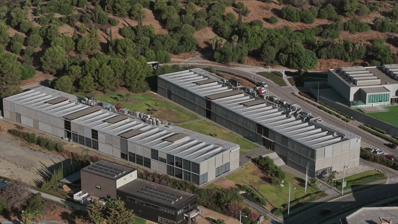 Drone perspective view of industrial complex with multiple large buildings surrounded by greenery, Málaga, Spain